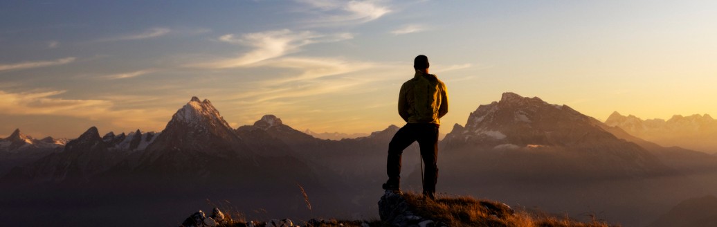 Bergsteiger steht auf Berg und schaut in den Fernblick