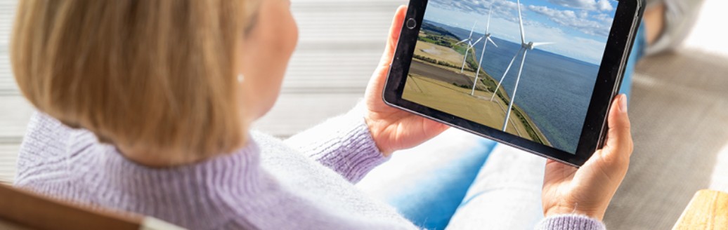 Magdalena Neuner sitzt im Sessel und schaut sich auf einem Tablet die Pangaea Life Investmentreise an